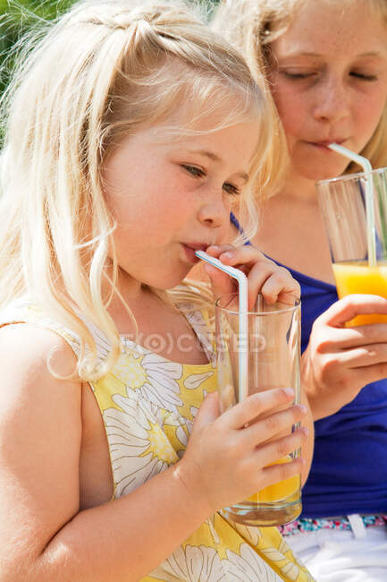 Две девушки пьют апельсиновый сок — стоковое фото