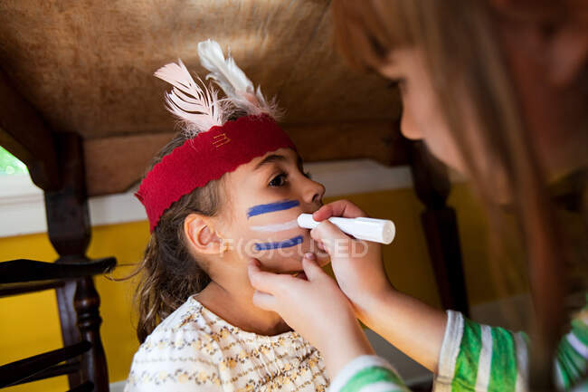 Girl putting Native American face paint on another girl — Stock Photo