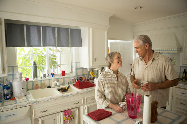 Старша пара на кухні, посміхаючись — стокове фото