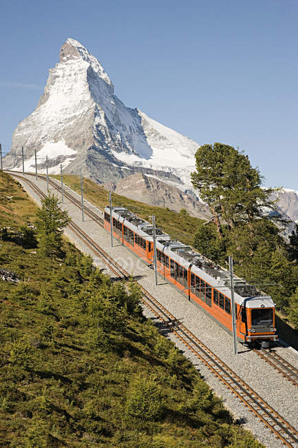 Train on mountain railway near snowcapped peak — Stock Photo