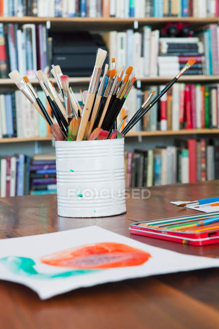 Children paintbrushes and paintings on table — Stock Photo
