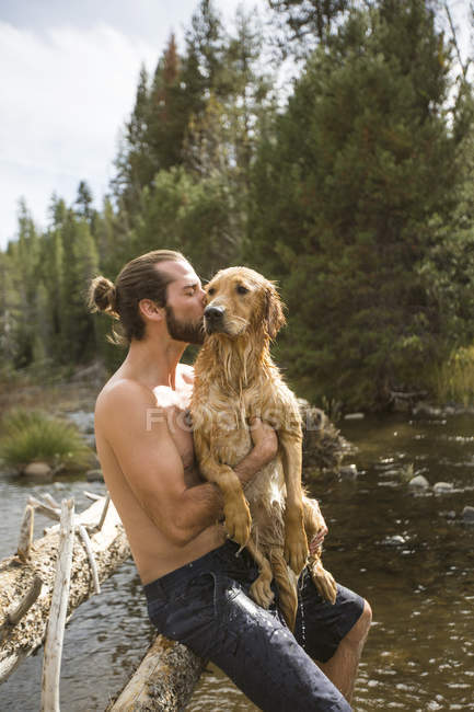 Молодой человек целует свою мокрую собаку на реке, озеро Тахо, Невада, США — стоковое фото
