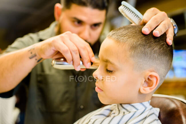 Barber shaving boy's hair — Stock Photo