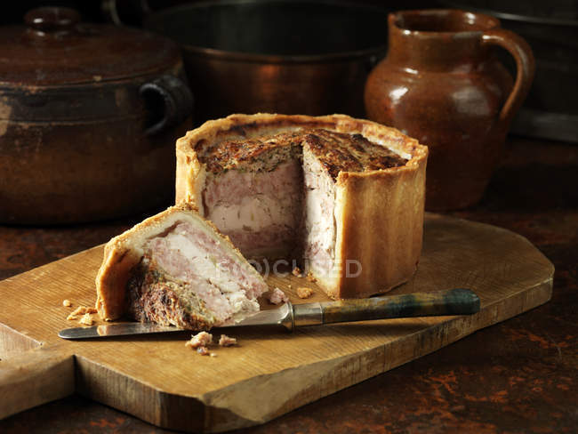 Layered pork, chicken and stuffing pie on chopping board — Stock Photo