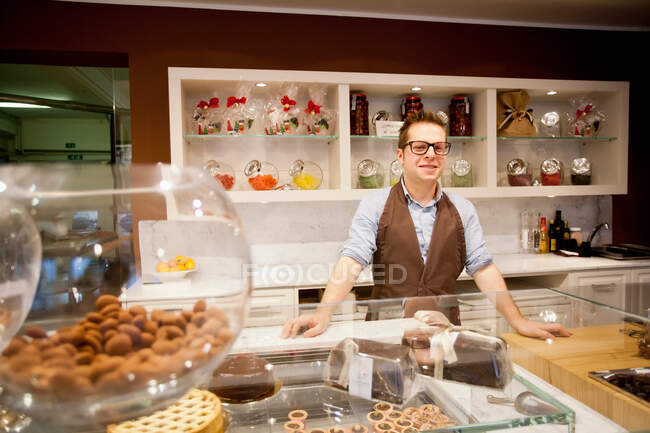 Cajero sonriendo detrás del mostrador de la panadería - foto de stock