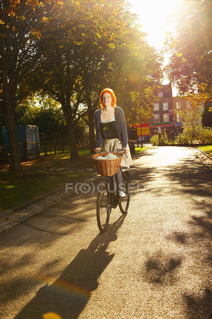 Молода руда жінка їде на велосипеді в парку — стокове фото