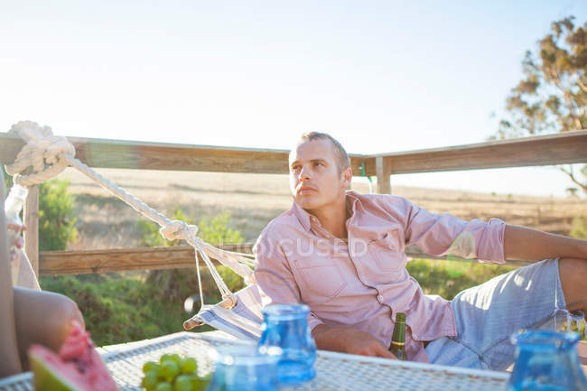 Jovem relaxante na rede na varanda — Fotografia de Stock
