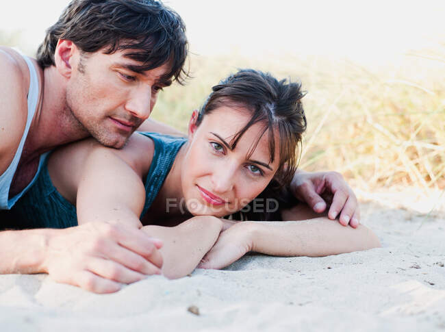 Casal deitado na areia sorrindo — Fotografia de Stock