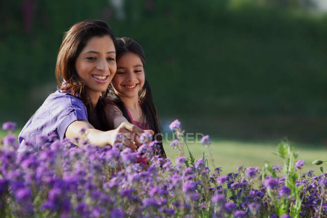 Madre e hija arrancando flores - foto de stock