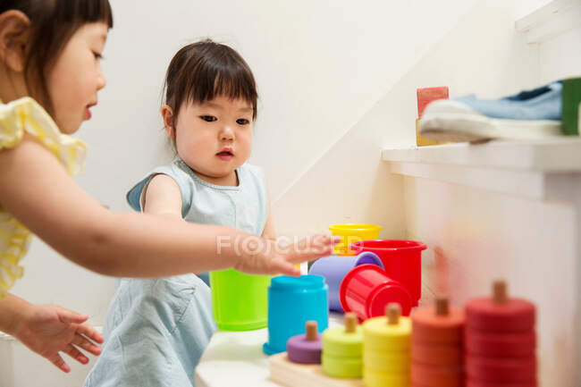 Dos hermanas jóvenes jugando con juguetes en la escalera - foto de stock