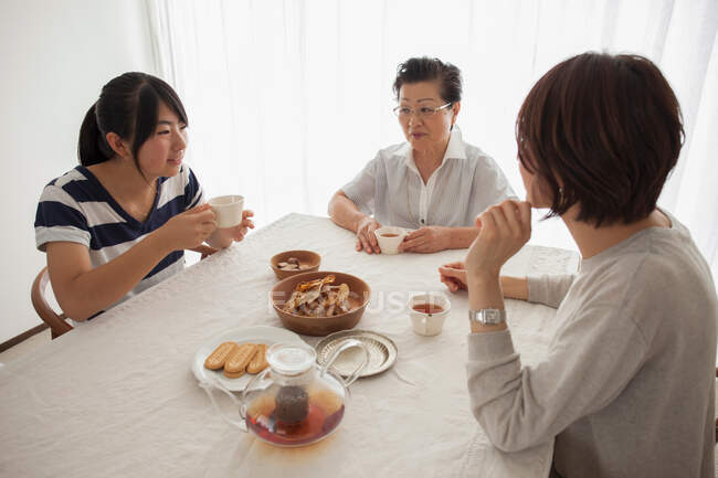 Familia de tres generaciones a la mesa - foto de stock