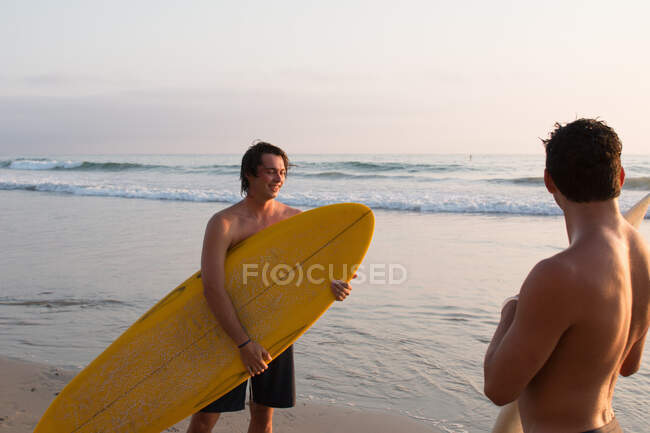 Deux jeunes hommes sur la plage, tenant des planches de surf — Photo de stock