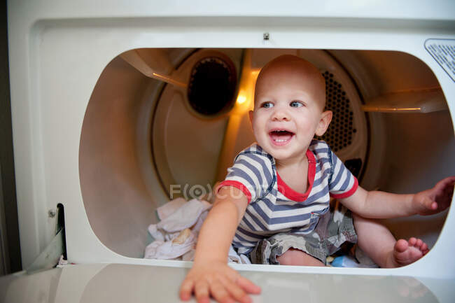 Niño sentado en secadora de ropa - foto de stock