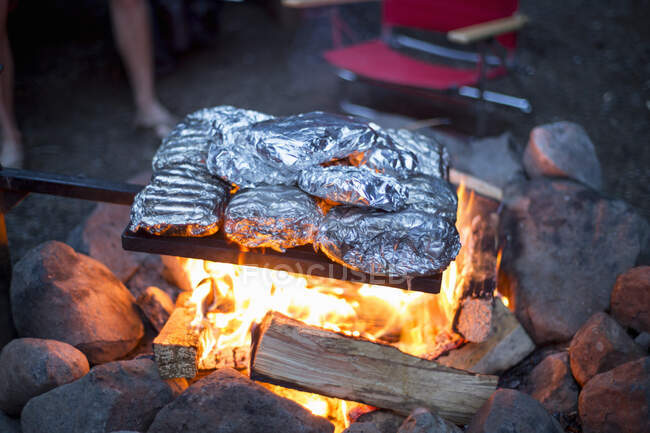 Lebensmittel in Alufolie eingewickelt, die über dem Lagerfeuer garen — Stockfoto