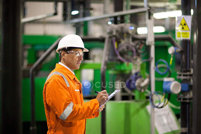Ingeniero inspeccionando maquinaria en fábrica - foto de stock