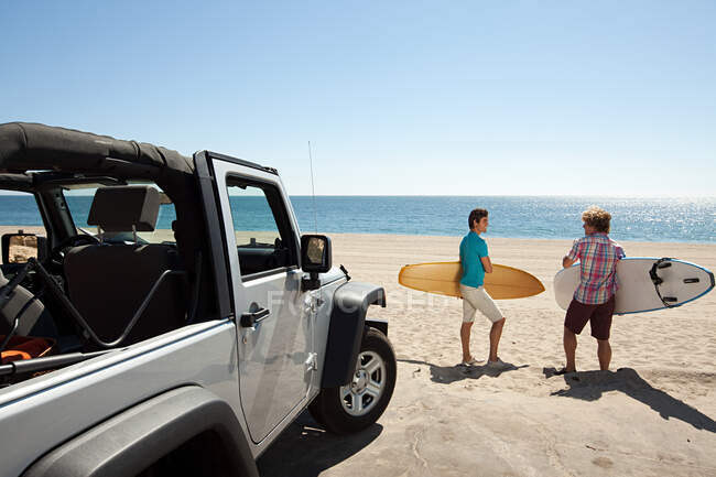 Two young men at the beach with surfboards — Stock Photo