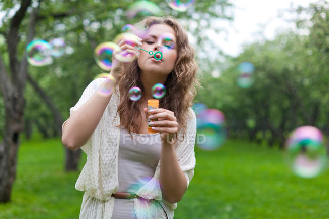 Jovem mulher soprando bolhas — Fotografia de Stock