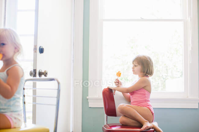 Дівчина сидить на стільці біля вікна, їсть лід повністю — стокове фото