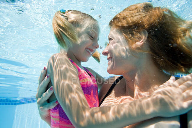 Madre e hija en la piscina - foto de stock