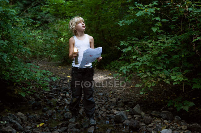 Мальчик в лесу с картой — стоковое фото