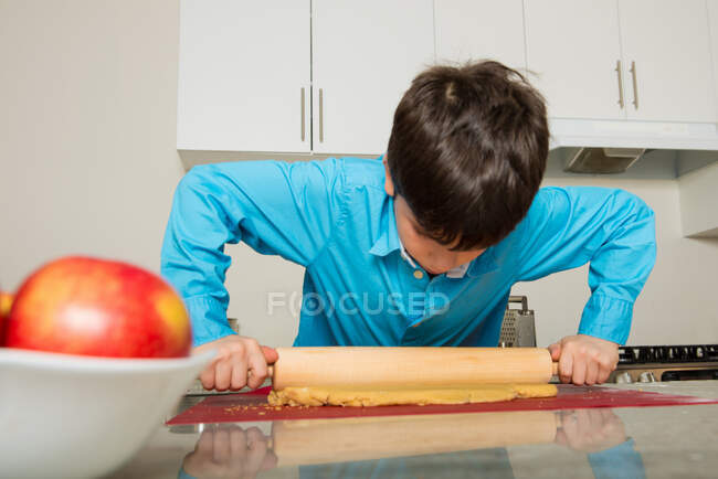 Chico rodando masa en la cocina - foto de stock