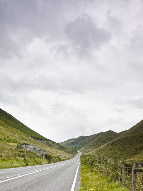 Vista da estrada rural e montanhas cobertas de vegetação exuberante — Fotografia de Stock