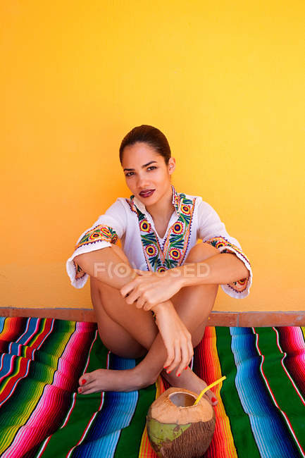 Woman sitting on ethnic style blanket with tropical fruit juice — Stock Photo