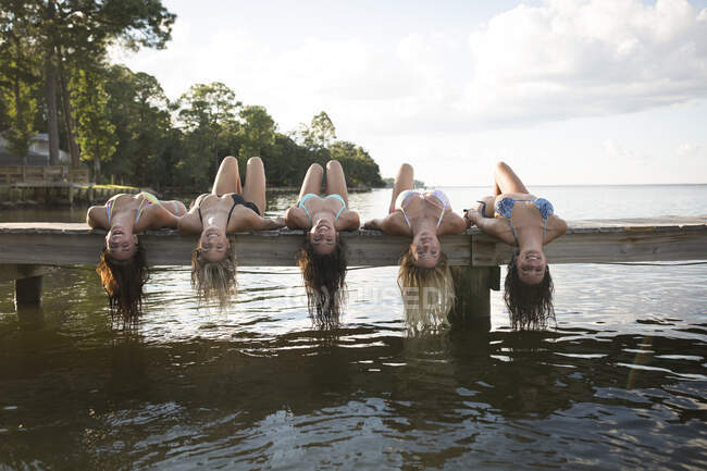 Portrait of women lying back on pier dangling long wet hair, Santa Rosa Beach, Florida, USA — Stock Photo