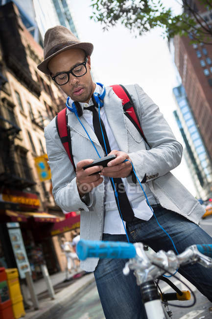Junger Mann mit Smartphone auf dem Fahrrad — Stockfoto
