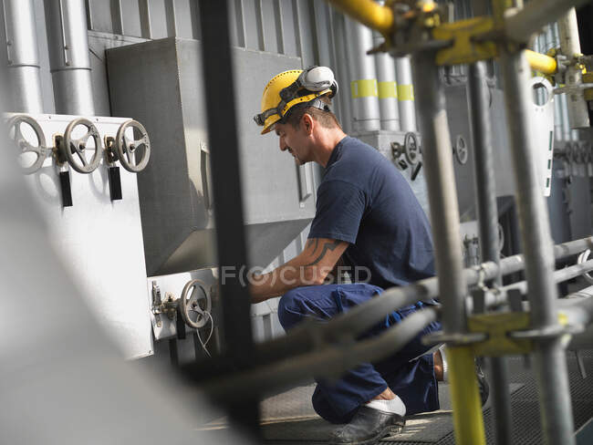 Worker operating machinery in factory — Stock Photo