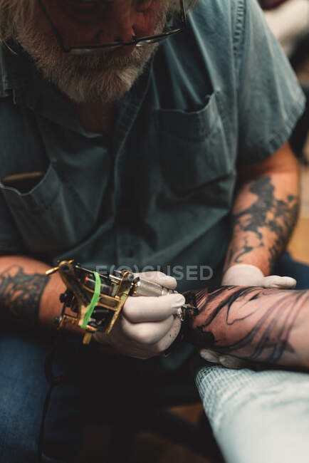 Tattooist tattooing young man's arm — Stock Photo
