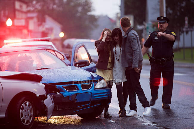 Jeunes et policiers sur les lieux d'un accident de voiture — Photo de stock
