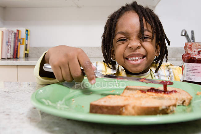 Porträt eines Jungen, der Marmelade auf Toast verteilt — Stockfoto