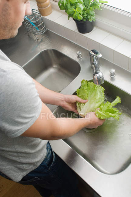 Homem lavando salada na cozinha — Fotografia de Stock