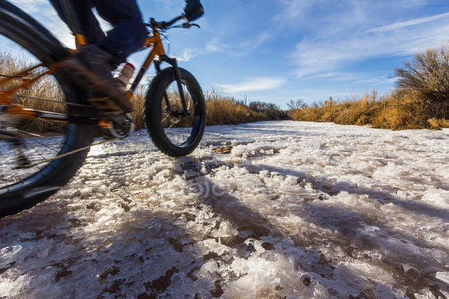 Mountain biker on snow in rural field — Stock Photo