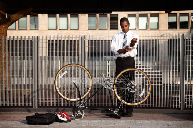 Giovane uomo d'affari maniche rotolamento per fissare la bicicletta — Foto stock