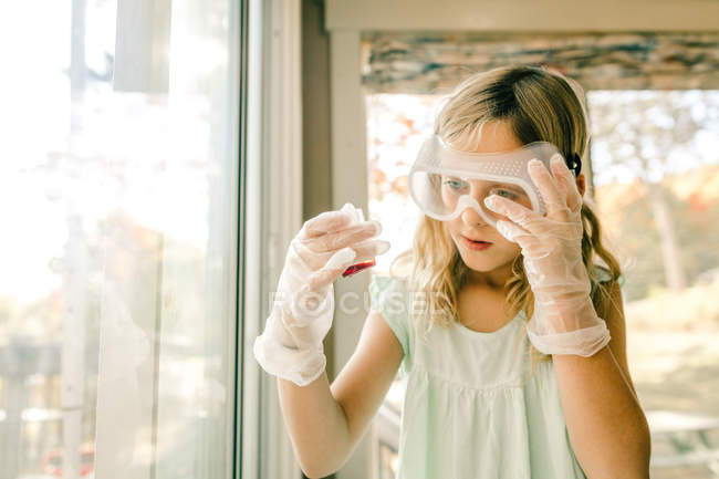 Chica haciendo experimento científico, mirando frasco de medición - foto de stock