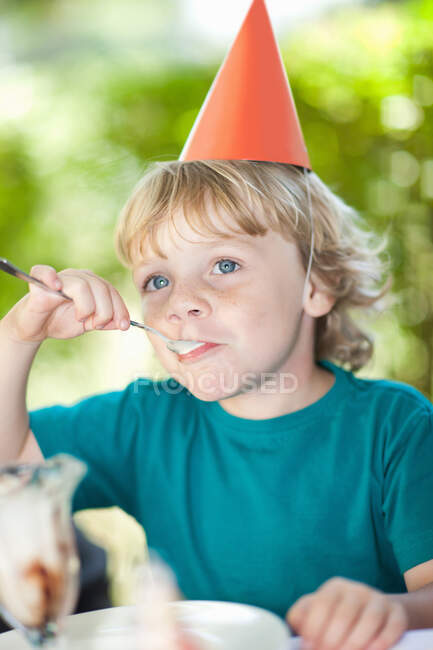 Chico comiendo helado helado en la fiesta - foto de stock