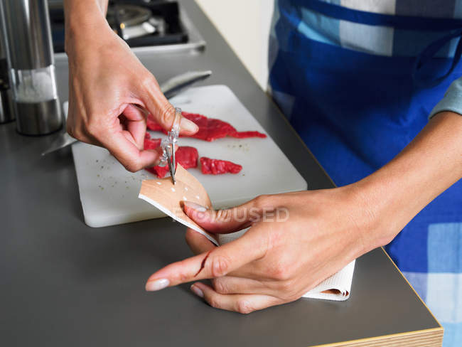 Frau schneidet Klebepflaster, um sich den Finger aufzusetzen — Stockfoto