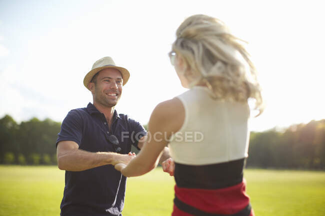 Couple holding hands and swirling around in park — Stock Photo