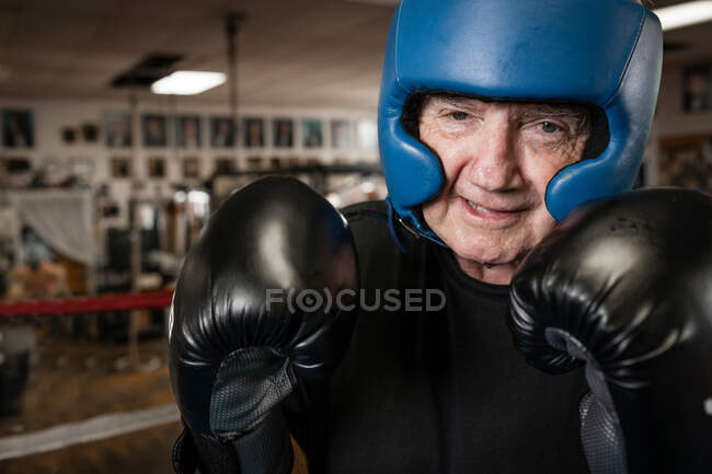 Senior trägt Boxhandschuhe und Helm — Stockfoto
