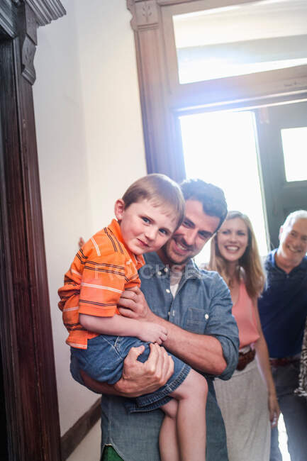 Vater hält Sohn lächelnd im Hausflur — Stockfoto