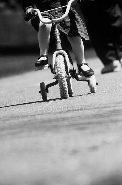 Imagen recortada de niña aprendiendo a andar en bicicleta - foto de stock