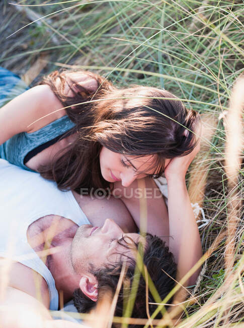 Couple couché dans l'herbe souriant — Photo de stock