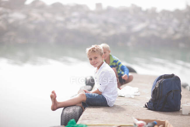Two young boys sitting on pier fishing — Stock Photo