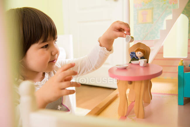 Chica jugando con casa de muñecas - foto de stock