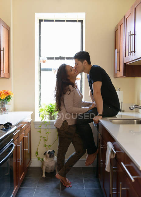 Jeune couple embrasser dans la cuisine — Photo de stock