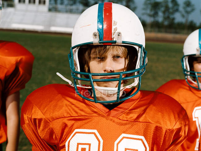 Menino vestindo capacete de futebol americano, olhando para longe — Fotografia de Stock
