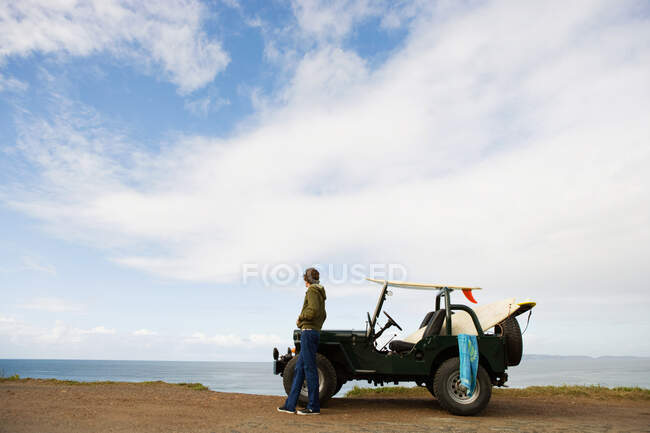 Молодий чоловік біля моря з позашляховиком — стокове фото