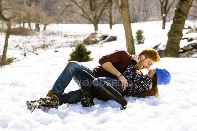 Романтическая молодая пара, лежащая в снежном Центральном парке, Нью-Йорк, США — стоковое фото
